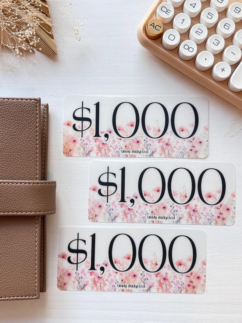 May include: Three pink and white floral patterned stickers with the text "$1,000" in black. The text "Smoky Bucketed" is printed in smaller font below the dollar amount on each sticker.