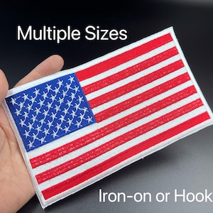 May include: A white embroidered American flag patch with red and blue stars and stripes. The patch is available in multiple sizes and can be ironed on or attached with a hook.