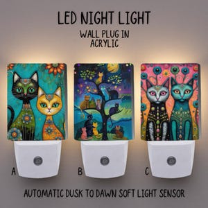 Puede incluir: Tres luces nocturnas LED con diseños de gatos coloridos. Cada enchufe de pared acrílico presenta una ilustración de gato única, con el texto "LED NIGHT LIGHT" y "AUTOMATIC DUSK TO DAWN SOFT LIGHT SENSOR".