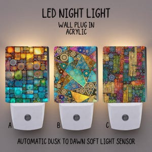 May include: Three LED night lights with vibrant geometric patterns. Each light features a white base and an acrylic front. The text "LED NIGHT LIGHT" and "AUTOMATIC DUSK TO DAWN SOFT LIGHT SENSOR" are displayed on the image.