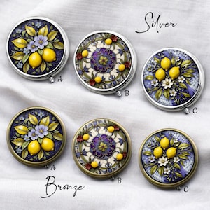 May include: Silver and bronze compact mirrors with floral and lemon designs. The silver compacts feature a mosaic-like pattern with lemons, flowers, and leaves. The bronze compacts have similar designs. The word "Silver" and "Bronze" are written on the image.