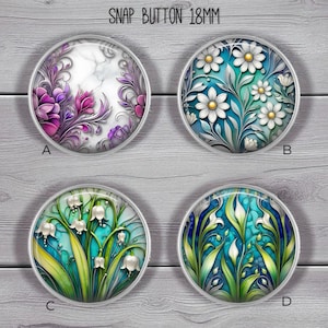 May include: Four round snap buttons, each 18mm in diameter, with floral designs. One features purple flowers on a marble background, another has white daisies on teal, a third shows lily of the valley, and the last has white leaves on teal.