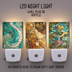 Puede incluir: Tres luces de noche LED con paneles decorativos de acrílico. Los paneles presentan diseños abstractos coloridos en turquesa, marrón y dorado. Cada luz de noche tiene una base blanca con un botón. El texto en la imagen dice "LED NIGHT LIGHT", "WALL PLUG IN ACRYLIC" y "AUTOMATIC DUSK TO DAWN SOFT LIGHT SENSOR".