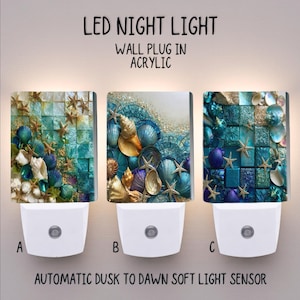 May include: Three LED night lights with wall plugs and automatic dusk to dawn sensors. Each acrylic light features a unique coastal design with blue, teal, and gold seashells and starfish. The text reads LED NIGHT LIGHT WALL PLUG IN ACRYLIC.