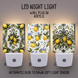 Peut inclure: Trois veilleuses à LED avec des motifs de citrons. Chaque veilleuse murale a une base blanche et un couvercle rectangulaire en acrylique avec un motif différent de citrons et de feuilles. Le texte "LED NIGHT LIGHT" et "AUTOMATIC DUSK TO DAWN SOFT LIGHT SENSOR" sont visibles.