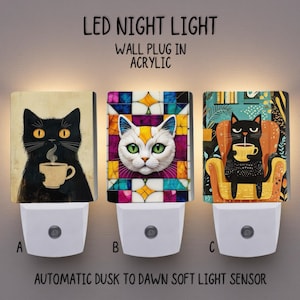 May include: Three acrylic LED night lights featuring cat illustrations. The wall plug-in lights have automatic dusk to dawn sensors. The cat designs include a black cat with a coffee cup, a white cat with stained glass, and a black cat in a chair with a coffee cup.