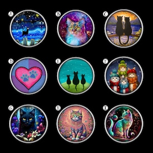 May include: Nine round cat-themed designs with silver rims. The designs feature various cat illustrations, including a black cat on a dock, a cat against a galaxy background, and cats in hats and scarves. Other designs include a heart with paw prints and cats on a hill.