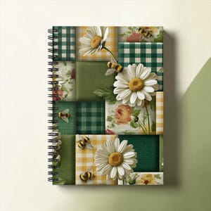 Puede incluir: Un cuaderno de espiral con una cubierta estilo collage que presenta cuadrados alternos de cuadros vichy verdes, verde sólido y patrones florales. El diseño incluye flores de margarita blancas con centros amarillos y pequeños abejorros.