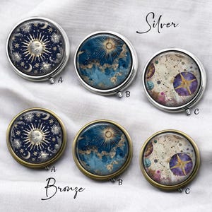 May include: A collection of round pill cases with celestial designs. The cases are available in silver and bronze finishes. The designs include a sun with a face, a sunburst, and a compass rose with a star. The word "Silver" and "Bronze" are written on the image.