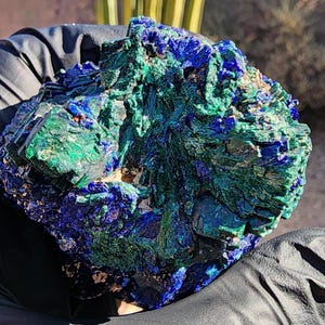 May include: A cluster of blue azurite and green malachite crystals. The crystals are rough and have a natural, unpolished look.