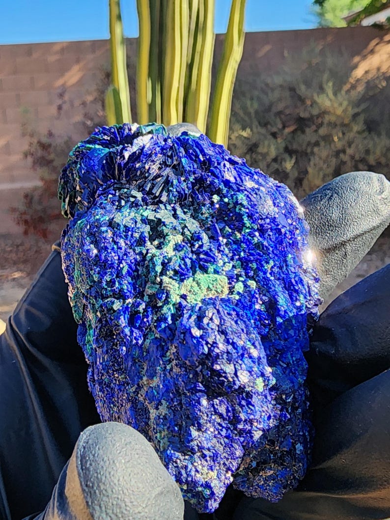 May include: A large, rough, blue and green azurite crystal with a sparkly, iridescent surface.