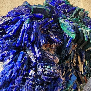 May include: Azurite and malachite crystal cluster with a deep blue and green color. The crystal has a rough, natural texture and is a beautiful example of these minerals.