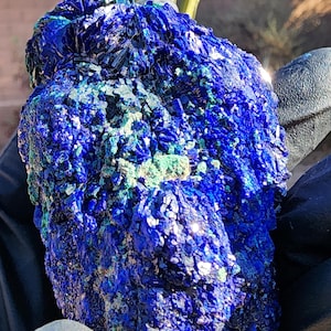 May include: A large, rough, blue and green azurite crystal with a sparkly, iridescent surface.