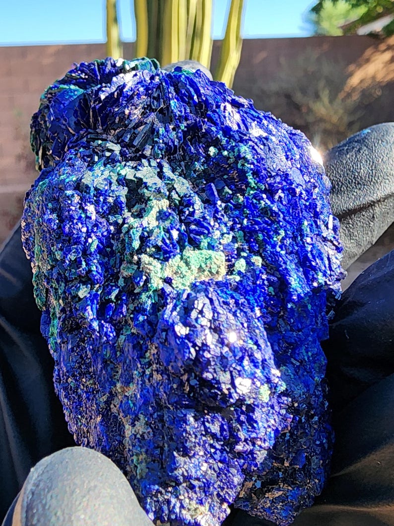 May include: A large, rough, blue and green azurite crystal with a sparkly, iridescent surface.