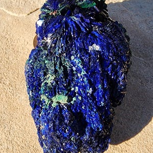 May include: A large, blue and green azurite crystal cluster with a rough, textured surface. The crystal has a deep blue color with green accents and a unique, organic shape.