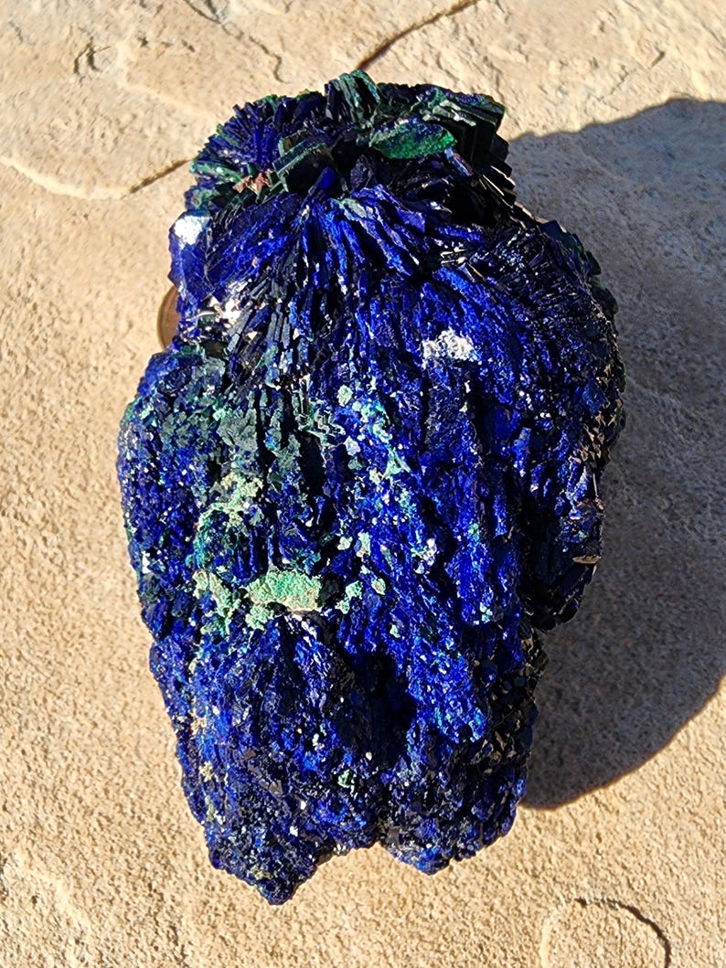 May include: A large, blue and green azurite crystal cluster with a rough, textured surface. The crystal has a deep blue color with green accents and a unique, organic shape.