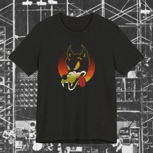 May include: Black t-shirt with a cartoon wolf head design. The wolf has a red tongue, white fangs, and yellow eyes, set against a red and orange circular background. The wolf graphic is outlined in yellow. The shirt has a crew neck.