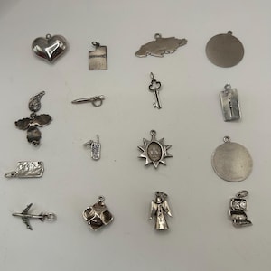 Könnte beinhalten: Eine Sammlung von 16 silbernen Anhänger, darunter ein Herz, ein Schlüssel, eine Sonne, ein Engel, ein Flugzeug, ein Telefon, ein Haus, ein Stern, eine Blume, ein Jamaika, ein Kreuz, ein Kreis und ein Rechteck.