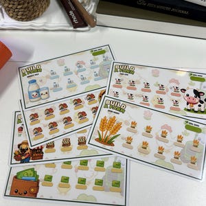 Könnte beinhalten: Eine Sammlung rechteckiger Spar-Tracker-Karten mit Illustrationen zum Thema Bauernhof. Jede Karte zeigt den Text Build A Farm sowie Symbole von Milch, Kühen, Weizen und Geldbörsen, begleitet von kleinen leeren Feldern zur Fortschrittsverfolgung.