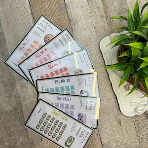 May include: A stack of colorful "Build a Bank" savings challenge cards. Each card features a different theme, including "Till No. 7", "Till No. 8", "Till No. 9", "Till No. 10", "The Vault", and "Bonus Cash". The cards are rectangular with black borders.
