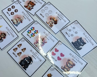 May include: A collection of rectangular cards with various animal illustrations, including a tiger, sheep, dog, unicorn, cat, owl, bear, and squirrel. Each card features the text "BUILD A BANK" and "ANGRY" with a number. The cards are arranged on a white surface.