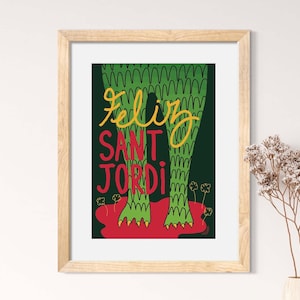 Könnte beinhalten: Ein grünes Monster mit dem Text "Feliz Sant Jordi" in gelben und roten Buchstaben. Das Monster hat grüne Schuppen und rote Füße. Der Hintergrund ist dunkelgrün.