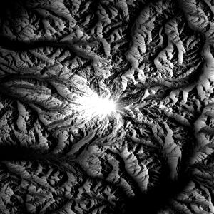 May include: A grayscale topographical map with a bright, central light source. The image depicts a detailed, textured landscape with valleys, ridges, and shadows, creating a dramatic, three-dimensional effect. The overall theme is nature and geography.
