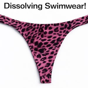 Può includere: Slip bikini rosa e nero con stampa leopardata. Il testo "Dissolving Swimwear!" è visualizzato sopra lo slip bikini. Lo slip bikini è uno stile perizoma con gamba alta.
