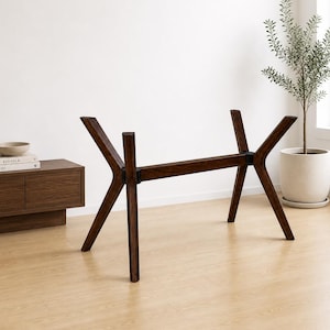 May include: Dark brown wooden table base with angled legs. The base has a rectangular center support and four angled legs, creating a modern, minimalist design. The table base is made of solid wood and is suitable for a dining table or desk.