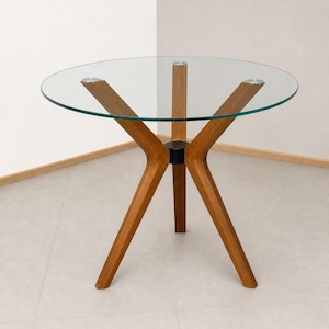 May include: A round glass-topped table featuring a clear circular surface supported by a central wooden base. The base consists of three angled wooden legs that meet at a central hub, providing a stable structure for the transparent tabletop.