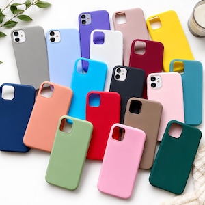 May include: A collection of solid-coloured silicone smartphone cases in various shades including grey, light blue, purple, white, yellow, maroon, teal, navy, peach, bright blue, black, pink, red, light green, tan, and dark green, each with a camera cutout.