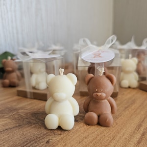 May include: A set of small, boxed, bear-shaped candles. The candles are in white and brown, and are packaged in clear boxes with white ribbon.