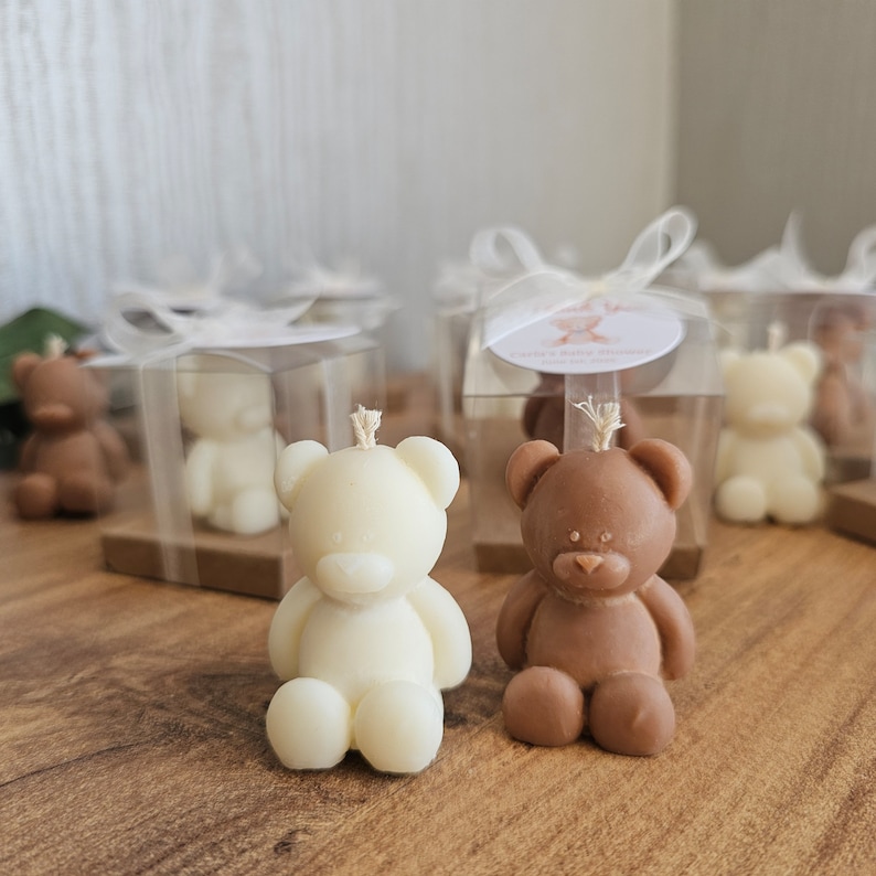 May include: A set of small, boxed, bear-shaped candles. The candles are in white and brown, and are packaged in clear boxes with white ribbon.