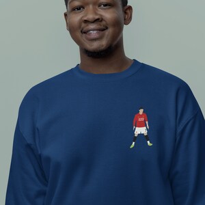 May include: A navy blue sweatshirt with a red and white soccer player graphic on the front. The player is wearing a red jersey with the number 7 on it.