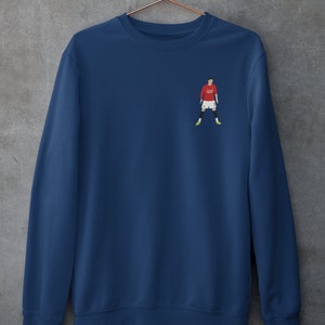 May include: A navy blue sweatshirt with a small embroidered image of a soccer player wearing a red jersey with the number "7" on it.
