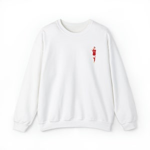 May include: White long-sleeve sweatshirt with a small embroidered image of a soccer player in a red and white uniform.