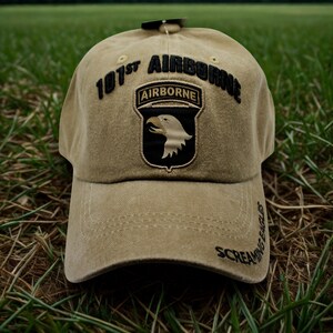 Op de afbeelding: Beige baseballcap met de tekst "101st Airborne" en een adelaarskop-patch. De cap heeft ook de tekst "Screaming Eagles". De cap is gemaakt van duurzaam materiaal en is geschikt voor buiten.