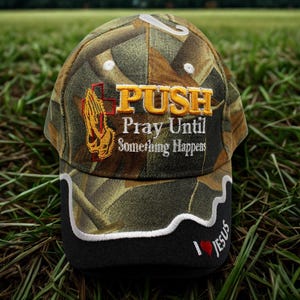 May include: Camouflage baseball cap with the text "PUSH Pray Until Something Happens." The cap features a black brim with the text "I ❤️ Jesus." The design includes a praying hands graphic and a cross.