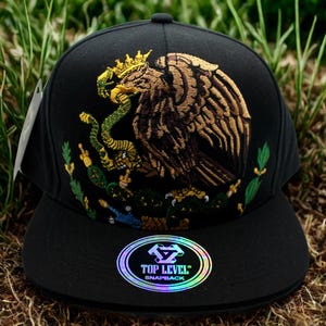 Gekrönter mexikanischer Adlerhut mit flachem Rand - Schwarze Snapback mit Goldschlangenadler-Stickerei. Mexiko Hut. Mexiko Trucker Hut