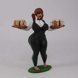 May include: A figurine of a woman wearing a black and white outfit, holding a tray with multiple beer mugs. The figurine is standing on a green base.