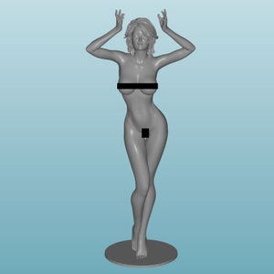 Peut inclure: Une figurine en 3D imprimée en gris d'une femme debout sur une base ronde. La figurine est posée avec les bras levés au-dessus de la tête.