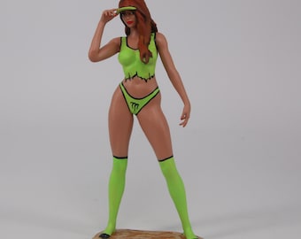 May include: A green and black painted figurine of a woman wearing a green visor, green top, green underwear, and green socks. The underwear has a black "Monster" logo.