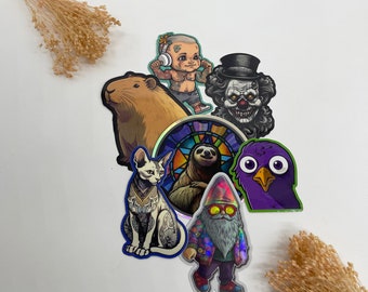 Puede incluir: Una colección de pegatinas holográficas de colores con una variedad de personajes y diseños, incluyendo un perezoso, un gnomo, un gato, un pájaro, un capibara, un payaso y un bebé con auriculares.
