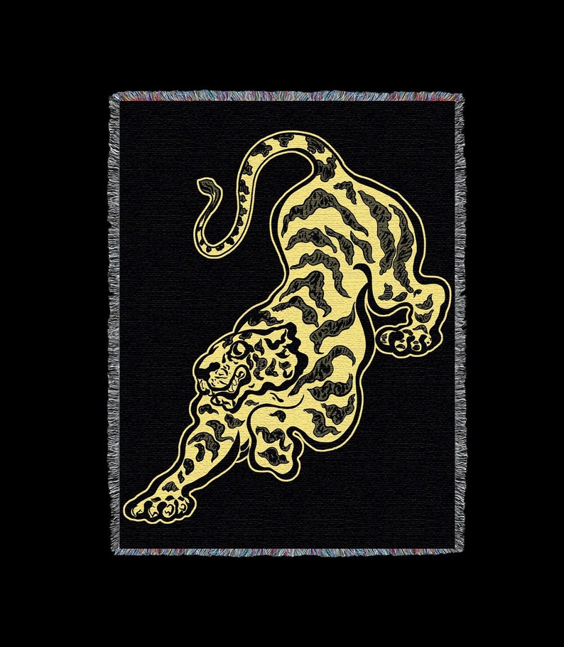 May include: A black and gold woven tapestry featuring a stylized tiger design. The tiger is depicted in a leaping pose with its head turned to the side. The tapestry has a fringed border.