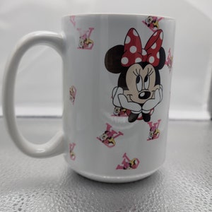 Pu&ograve; includere: Tazza in ceramica bianca con un design Minnie Mouse rosa e rosso. La tazza presenta una grande immagine di Minnie Mouse con un fiocco rosso e pois bianchi. Lo sfondo &egrave; bianco con motivi a "V" rosa.