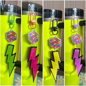 May include: Four colorful keychains with a lightning bolt design and a small cube with a colorful pattern. The keychains are attached to a metal ring and have a clip on the top.