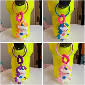 May include: Four yellow tumblers with different colored unicorn charms attached to the lids. The unicorns are pink, blue, purple, and orange.