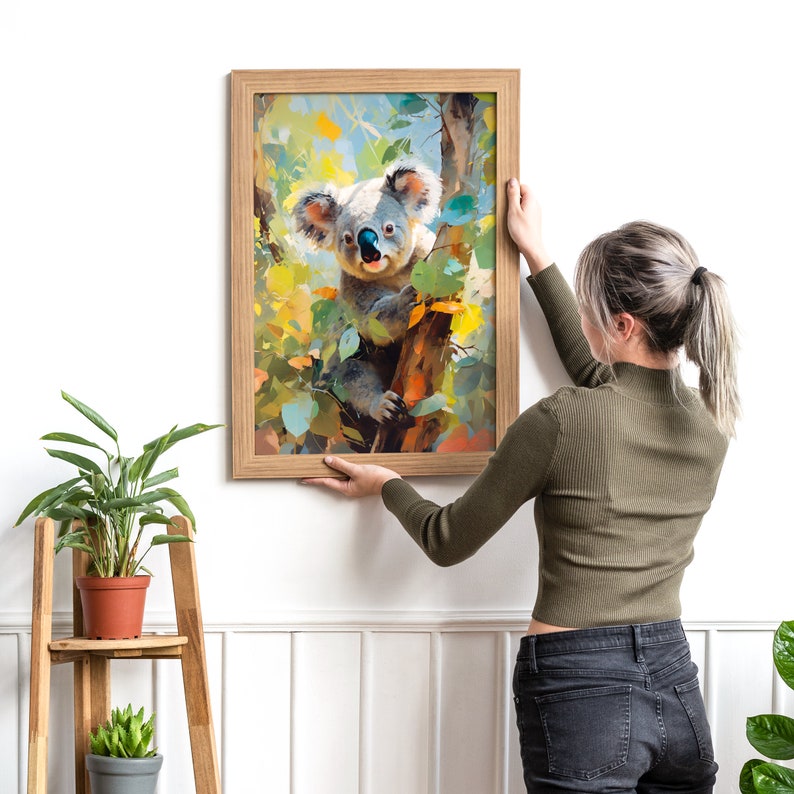 May include: A framed painting depicting a koala bear perched on a tree branch. The koala is looking directly at the viewer with a curious expression. The painting is rendered in a realistic style with bright colours.