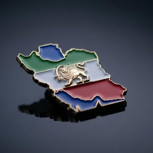 Puede incluir: Un colorido pin esmaltado con forma de mapa, con secciones verdes, azules, blancas y rojas y un borde dorado. Un emblema de león dorado está centrado en el área blanca. El pin está sobre una superficie oscura y reflectante.