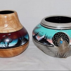 May include: Two handcrafted gourd vases. One is light brown with a carved top and a painted scene of a deer and mountains. The other is gray and turquoise with a dreamcatcher and feathers.